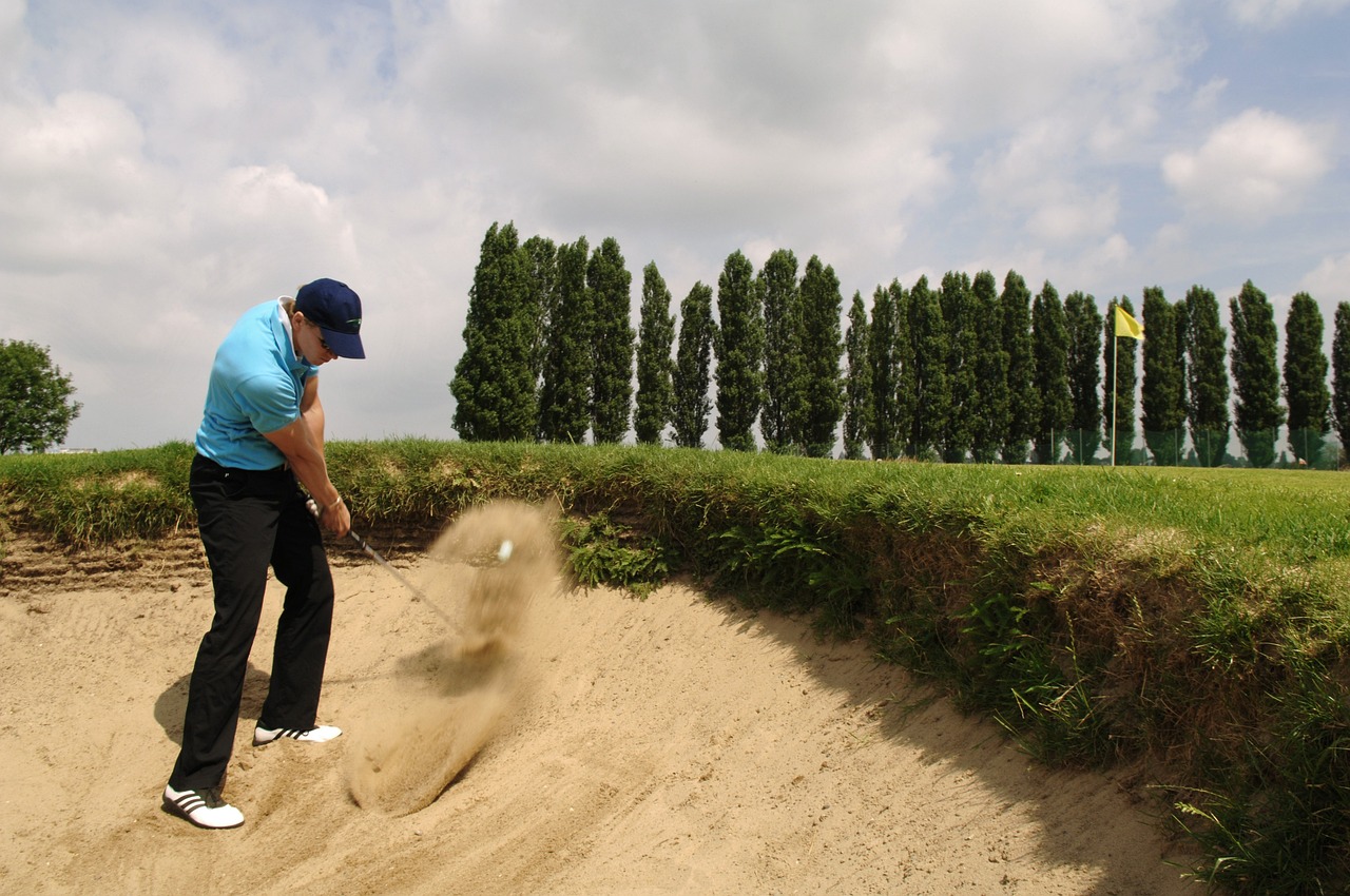 man slår golfboll från en bunker